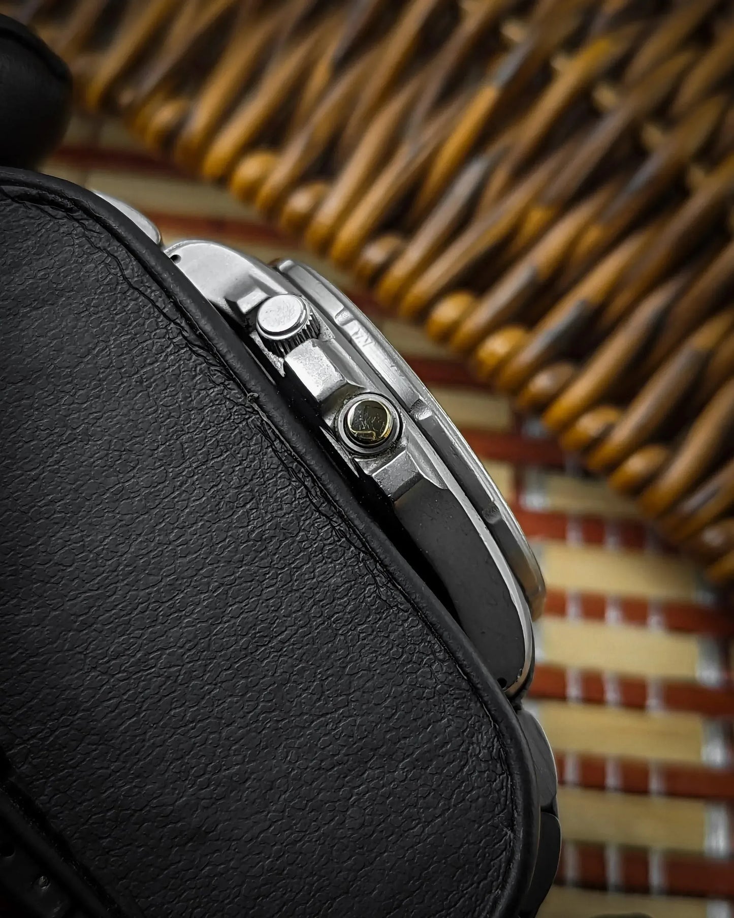 Close-up of a stainless steel field watch case and crown with leather strap detail