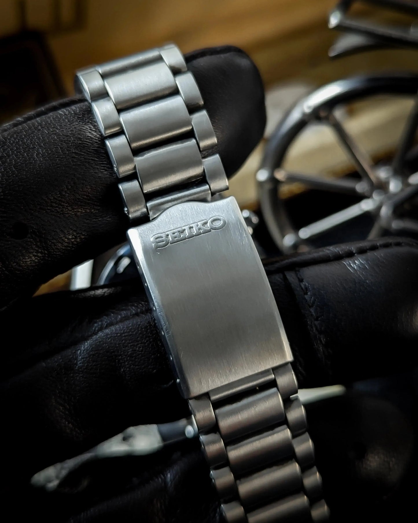 Close-up of Seiko stainless steel watch bracelet clasp held by gloved hand