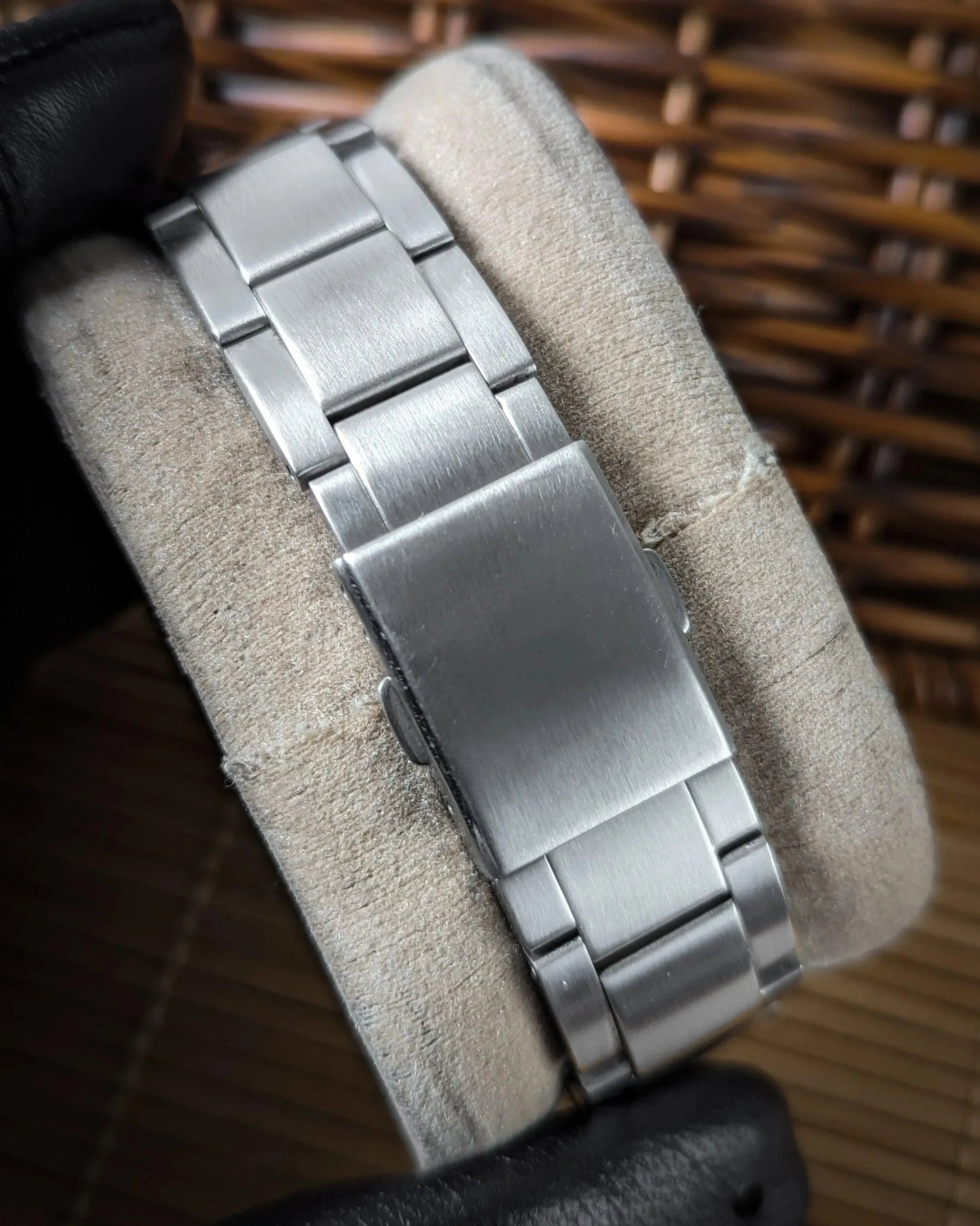 Stainless steel watch bracelet clasp detail on cushion, close-up