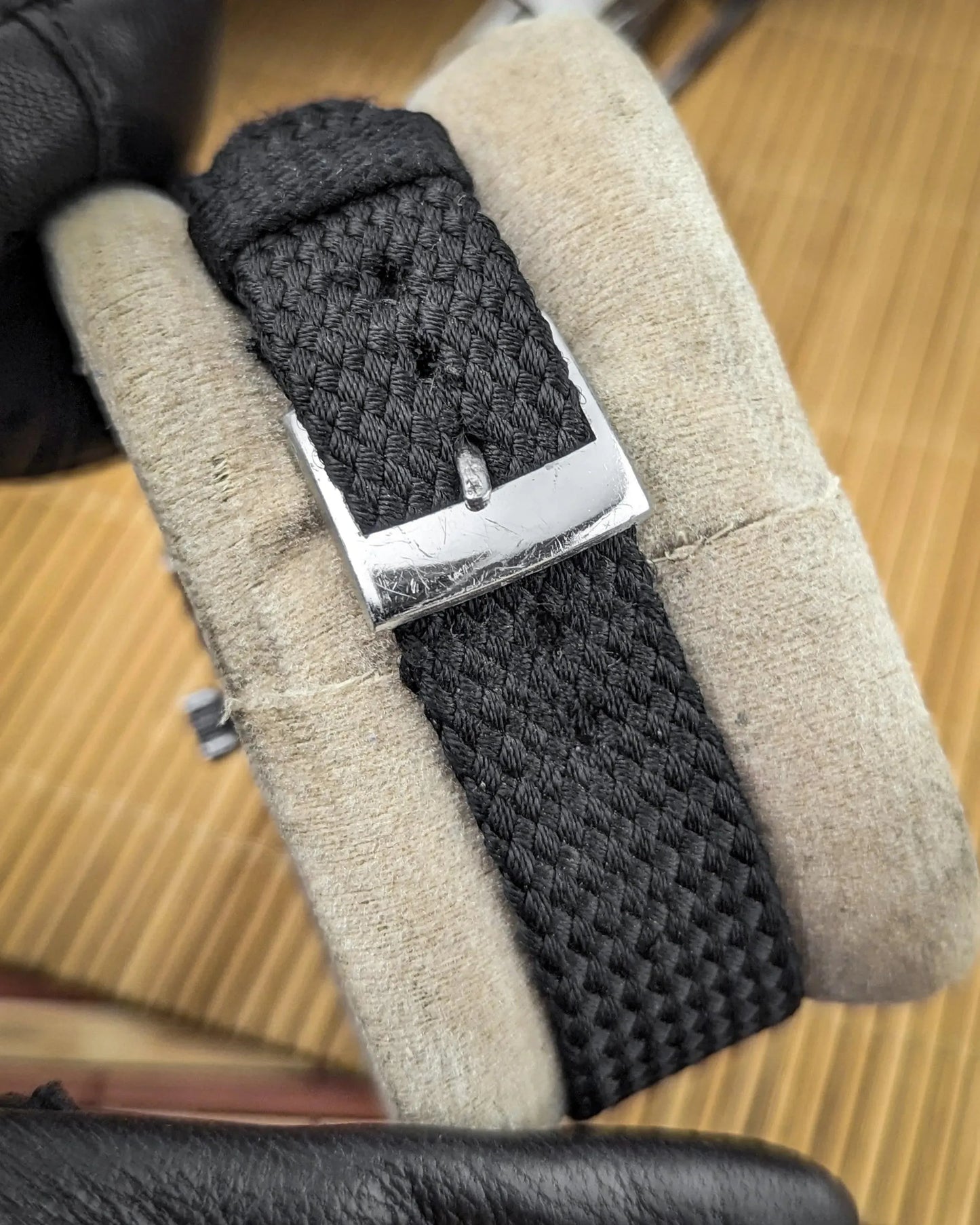 Black woven nylon watch strap with silver buckle on display cushion