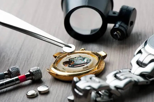 Close-up of vintage watch repair with open case, tools, and battery on wooden surface